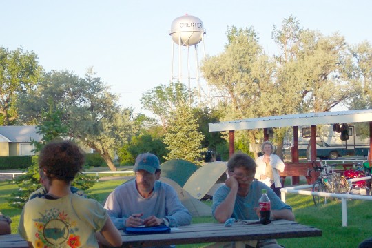 People sitting at picnic table with Chester water tower in background