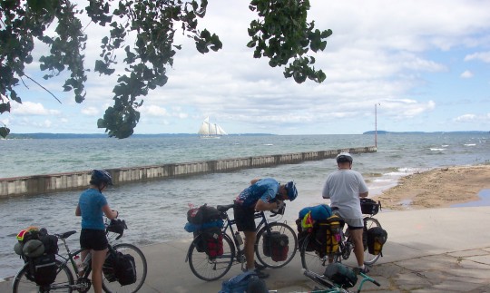 Cyclists on the dock with sailing ship on the horizon