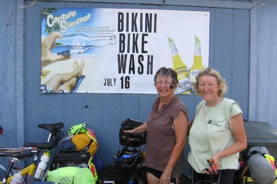 Jeanne and Carol in front of a 'Bikini Bike Wash' sign