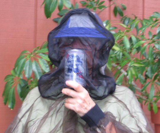 Jeanne drinking a beer inside her mosquito head net