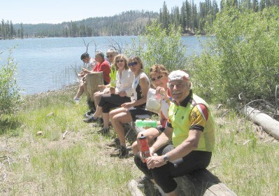 Riders sitting on a large log beside the lake