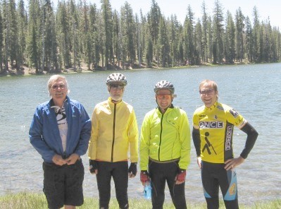 Four cyclists standing in front of the lake
