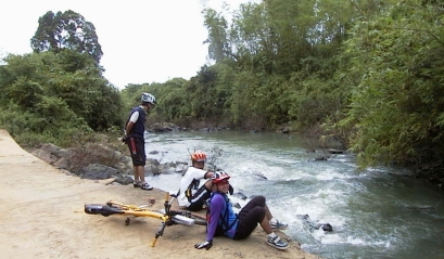 Several cyclists sitting at the edge of a stream