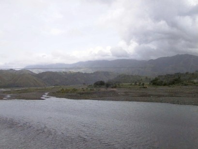 Water in foreground with mountains and clouds in the distance