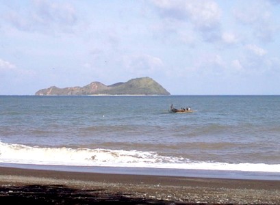 Beach with boat and rocky island offshore