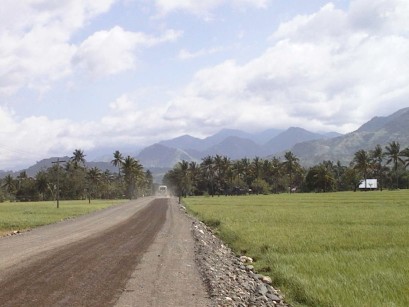 Gravel-paved road with mountains in the distance shrouded in clouds